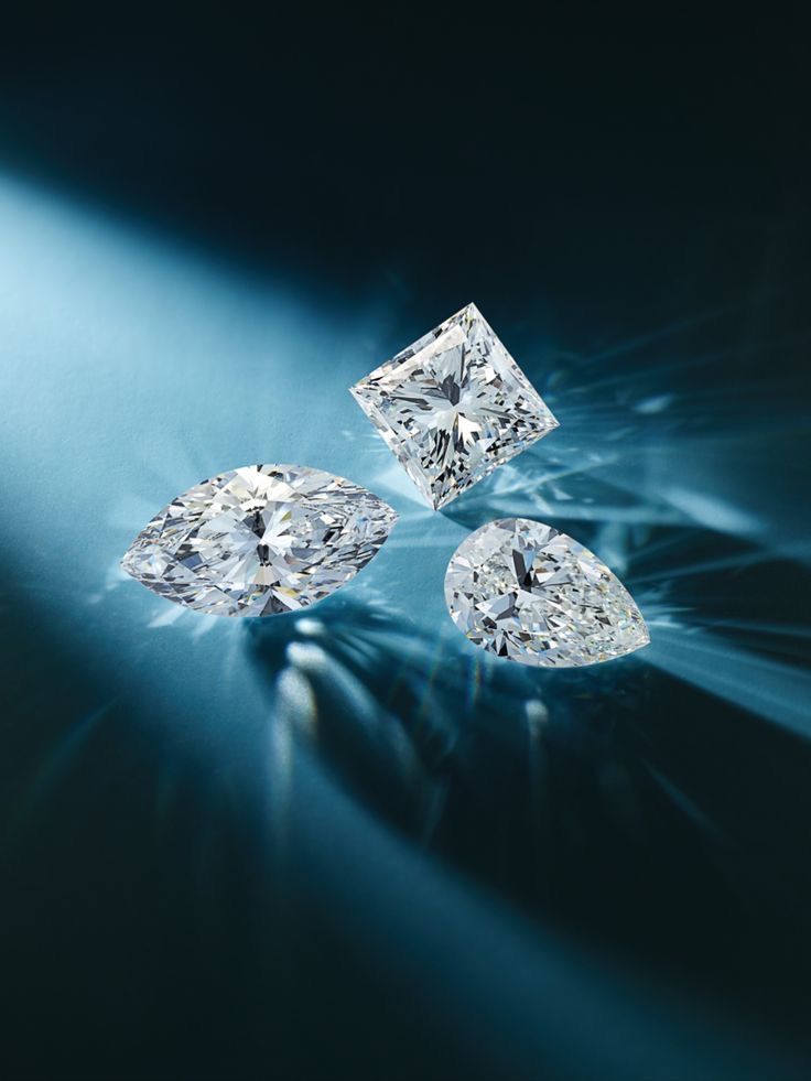 Three colourless diamonds showing crisp internal faceting under cool studio light